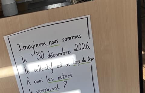 Feuille manuscrite sur un panneau en bois : imaginons, nous sommes le 30 décembre 2026, le collectif est au top, à quoi le verrait-on ?