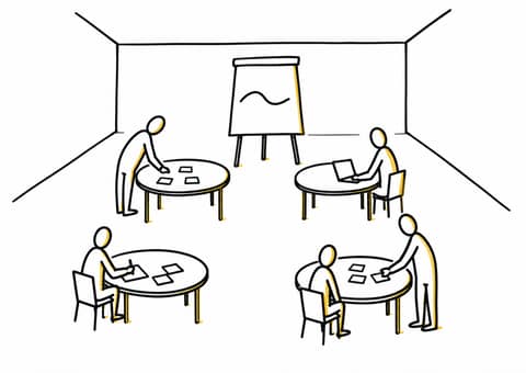 Une salle avec quatre tables rondes et un paperboard, où trois personnes posent des feuilles et préparent un ordinateur avant l'arrivée du groupe.